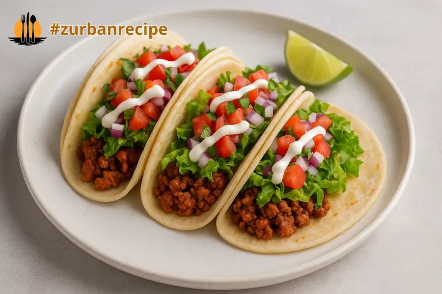 Three tacos with seasoned beef, lettuce, tomatoes, and onions arranged on a bright plate for Taco Recipes