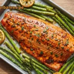 Sheet Pan Salmon with roasted asparagus and fresh lemon slices on a baking pan.