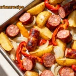 Overhead view of a sheet pan sausage dinner with roasted peppers, onions, and potatoes, showcasing vibrant colors and crisp textures.