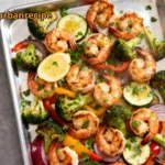 Sheet Pan Shrimp Scampi with roasted broccoli, peppers, and zucchini on a baking tray.
