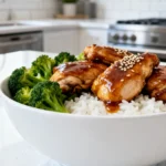 Cheap teriyaki chicken meal prep featuring juicy glazed thighs, steamed broccoli, and white rice in a white bowl.