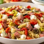 Antipasto Pasta Salad with rotini pasta, Genoa salami, mozzarella pearls, provolone cheese, cherry tomatoes, black olives, pepperoncini, roasted red peppers, and Italian vinaigrette, an easy make-ahead Italian pasta salad for potlucks, BBQs, and summer gatherings.
