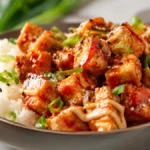 Sticky Bang Bang Tofu served over fluffy jasmine rice with crispy golden tofu cubes coated in a creamy sweet and spicy bang bang sauce, topped with green onions and sesame seeds.